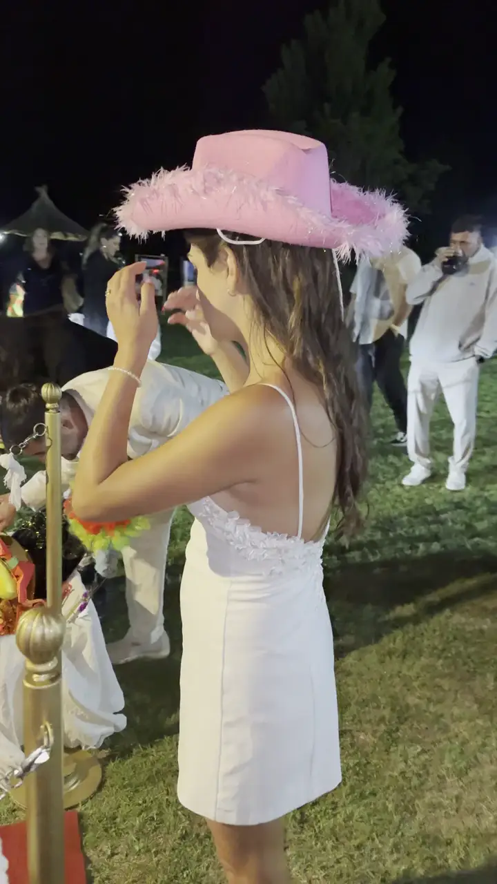 Invitada con sombrero interactuando con el espejo mágico en la entrada de la fiesta