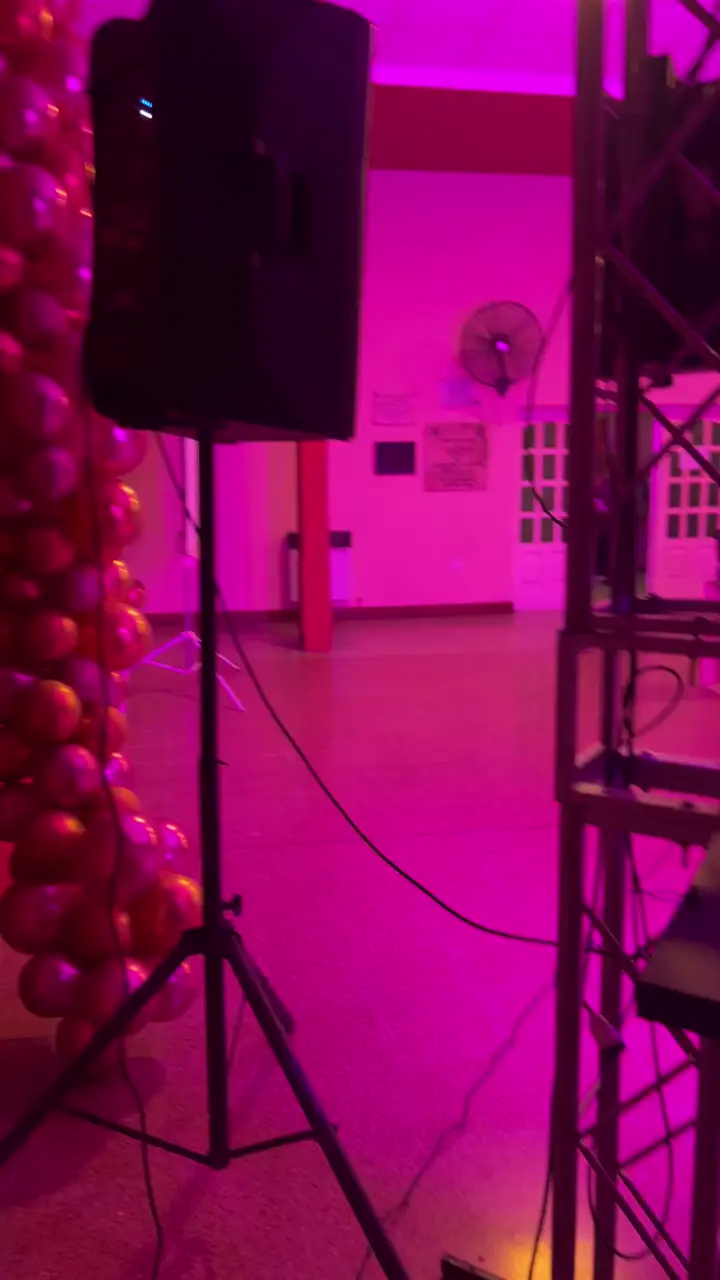 Parlantes, truss y cabeza móvil con iluminación rosa en salón